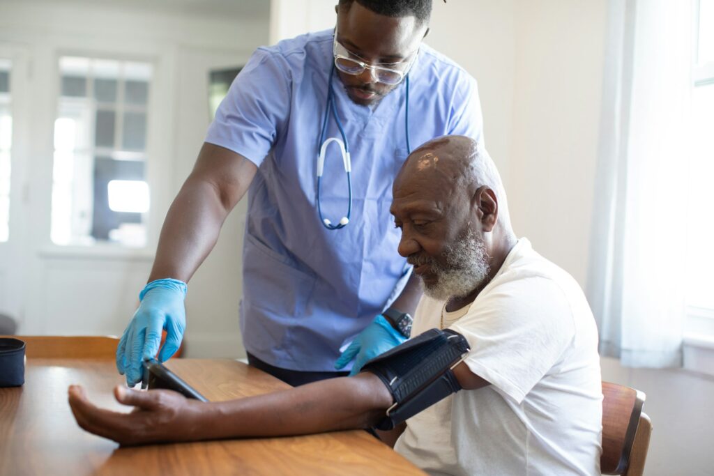 Elderly black man is having his blood pressure measured by a black male healthcare professional